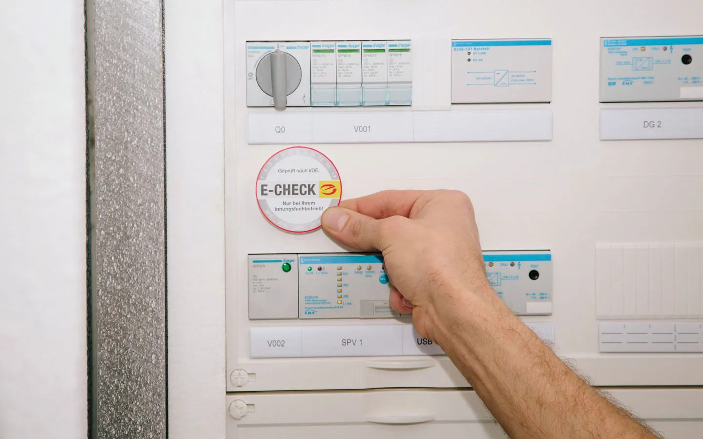 E-CHECK - Mitarbeiter klebt in der Verteilung die E-CHECK Plakette an &middot; Huhnold Elektro