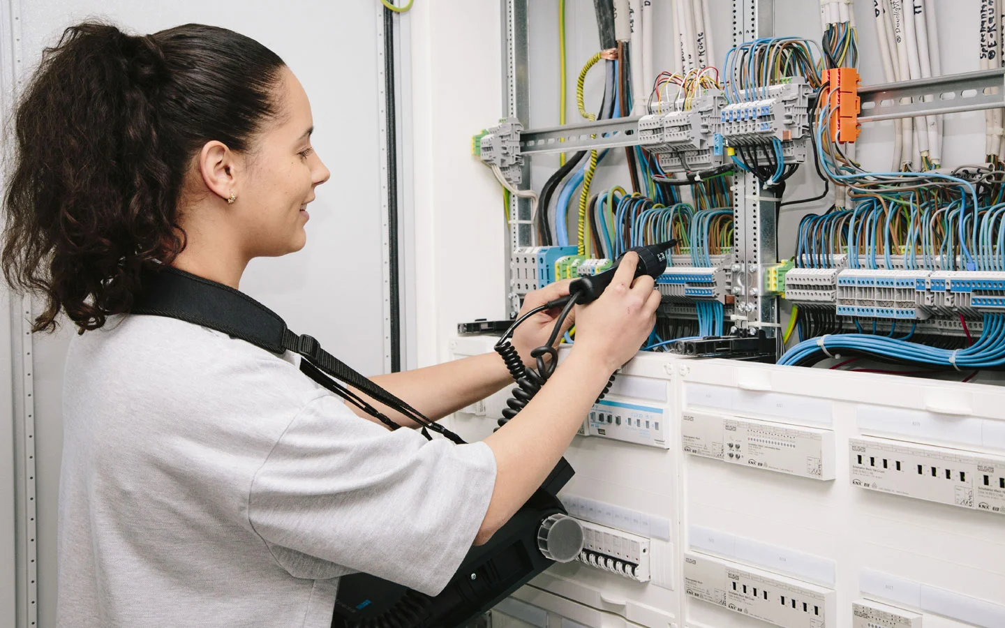 E-CHECK - Mitarbeiterin prüft im Schaltschrank mit einem Meßgerät &middot; Huhnold Elektro